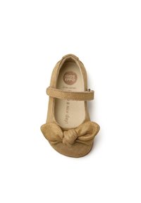 Bailarina de ante marrón claro con un detalle de lazo en la puntera y una correa de velcro. Interior suave con el logotipo de la marca impreso en la plantilla.