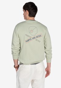 Sudadera verde menta con un gráfico de calavera y texto en la parte trasera, con un cuello redondo acanalado y puños, y un corte relajado.