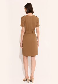 Brązowa sukienka do kolan z krótkimi rękawami, z paskiem w talii i akcentami na ramionach; gładki materiał i zamek błyskawiczny z tyłu.