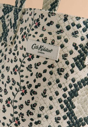 Zbliżenie na materiałową torbę typu tote z czarnymi i różowymi kwiatowymi oraz geometrycznymi wzorami oraz metką marki Cath Kidston London.