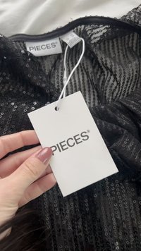 Top preto de lantejoulas com decote redondo, etiqueta com a marca "PIECES", com textura de tecido lisa e uma camada inferior transparente.