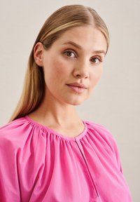 Rosa Bluse mit gerafftem Ausschnitt und einer Knopfschließe vorne. Glattes, leichtes Gewebe mit weicher Textur und lockerer Passform.
