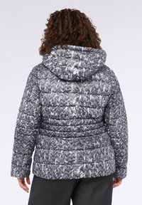 Giubbotto semplice grigio con cappuccio, caratterizzato da un motivo a zigzag in bianco e nero. Il design include sezioni trapuntate per una maggiore texture.