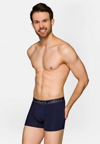 Granatowe slipki chłopięce o miękkiej fakturze, z kontrastującym paskiem z logo i dopasowanym krojem, zapewniające wygodne i przylegające dopasowanie.