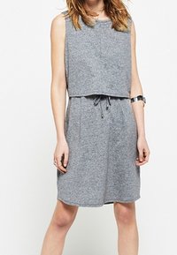 Robe sans manches grise avec un haut court, coupe ample, taille élastique et cordon de serrage. Le tissu semble doux avec une texture légère.