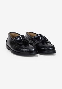 Mocasines de cuero negro con un diseño de costura, acentos de borlas prominentes y una suela de goma plana. Acabado suave.