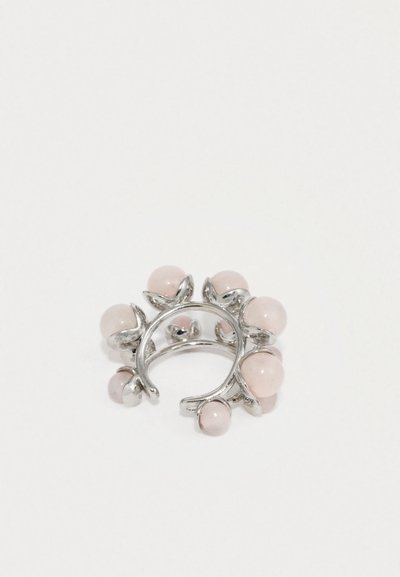 Strieborný prsteň s otvoreným pásom, zdobený ôsmimi okrúhlymi svetloružovými kameňmi rovnomerne rozmiestnenými okolo neho.
