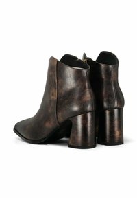 Bottines en simili cuir marron avec un bout pointu et des talons épais. Présentent une finition texturée subtile et une fermeture éclair à l'arrière.