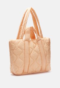 Sac fourre-tout matelassé pêche avec des anses horizontales texturées et une forme rectangulaire. Il présente un tissu doux et un motif de couture ondulé.