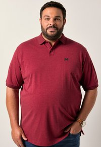 Burgundská polokošile s límečkem a krátkým rukávem. Na levém prsu má malé černé logo a je vyrobena z jemné látky.