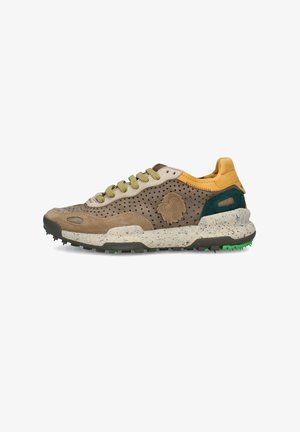 Zapatilla baja de ante beige y marrón con perforaciones, detalles amarillos, suela moteada, agarre verde y logotipo lateral texturizado.
