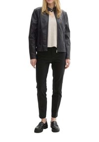 Veste en cuir noir au design épuré, avec fermeture éclair à l'avant et poches latérales, associée à un pull léger et un pantalon noir, complétée par des mocassins noirs.