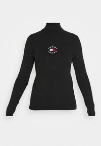 Czarny sweter typu golf o prążkowanej fakturze, z okrągłym haftowanym logo "TOMMY JEANS" w białym i czerwonym kolorze na piersi.