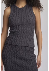 Harmaa neulotut hihattomat paita, jossa on teksturoitu letkukuvio ja kerroksellinen helma. Materiaalin vaikutelma on pehmeä, ja se on muotoiltu kapeaksi.