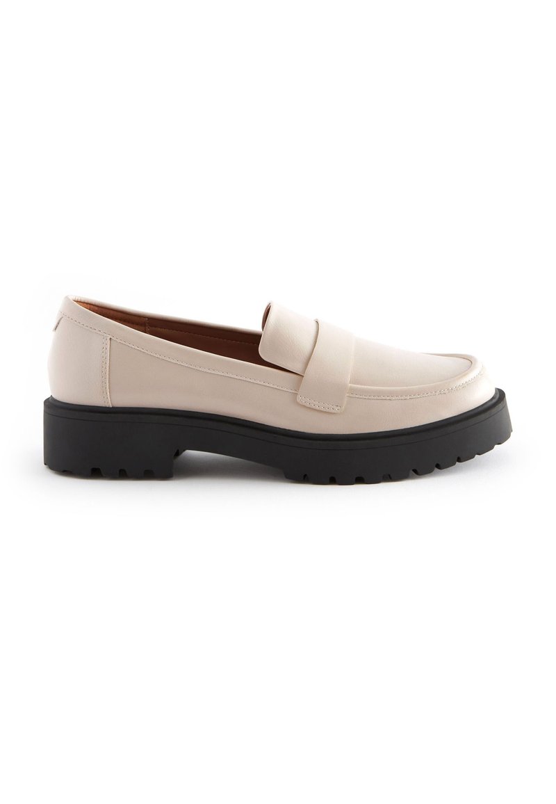 Beige nahka loaferit, joissa on leveä hihna, pyöreä kärki ja musta, uritettu kumipohja. Sujuva pinta, jossa on ompelut yksityiskohdat.