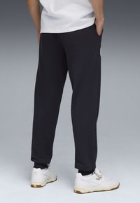 Marineblauwe joggerbroek met een ontspannen pasvorm, omgeslagen enkels en zijkanten met zakken. Gecombineerd met witte sneakers met een geel accent.