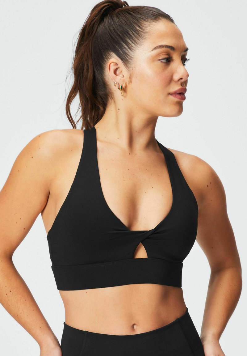 Zwarte sportbeha met een diepe V-hals, een gedraaide voorkant met een kleine uitsnijding en brede schouderbanden. Gemaakt van rekbaar materiaal.