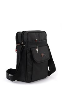 Schwarze Stoff-Umhängetasche mit einem Vorderklappenverschluss, mehreren mit Reißverschluss versehenen Fächern, einem verstellbaren Schulterriemen und einem kleinen Anhänger. Strukturierte Oberfläche.