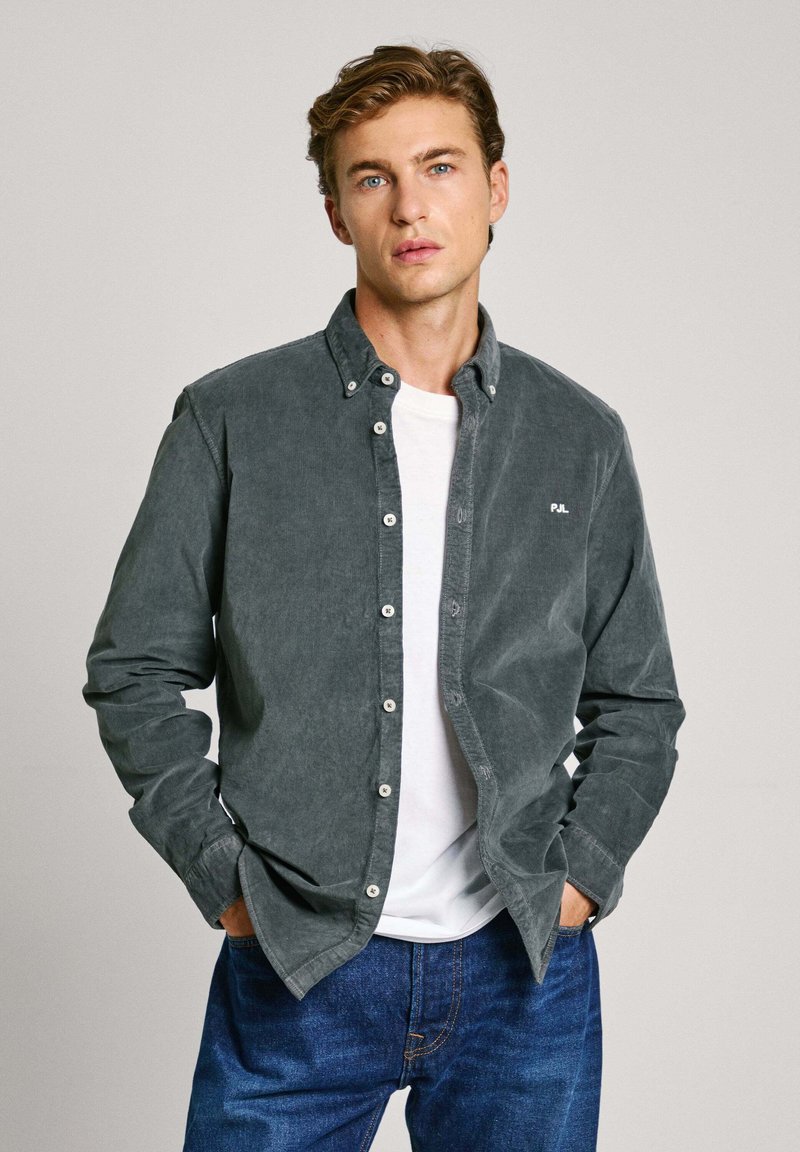 Grijze corduroy button-up shirt met een witte crew neck t-shirt eronder. Heeft knoopsluiting, lange mouwen en een subtiele logo-detail.
