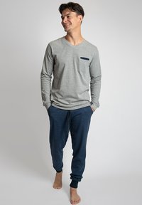 Grijze langsgestrikte V-hals shirt met een marineblauwe zak, gecombineerd met marineblauwe joggers met een trekkoord en taps toelopende manchetten.