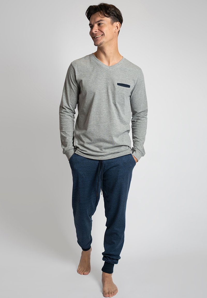 Grijze langsgestrikte V-hals shirt met een marineblauwe zak, gecombineerd met marineblauwe joggers met een trekkoord en taps toelopende manchetten.