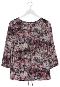 Blouse à manches longues avec motif floral rose, noir et bleu clair, suspendue à un cintre blanc.