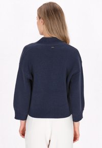 Maglione lavorato a maglia blu navy con scollatura rotonda, polsini e orlo a coste, caratterizzato da un piccolo dettaglio del logo sul retro. Tessuto morbido, vestibilità rilassata.