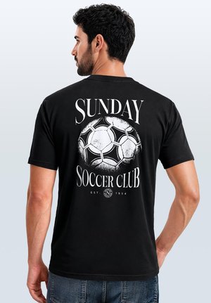 Mann trägt schwarzes T-Shirt mit weißem Fußballgrafik und Schriftzug "Sunday Soccer Club" auf dem Rücken.