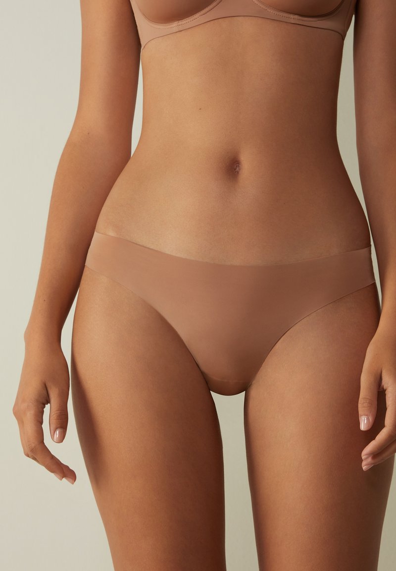 Naadloze nude bikini onderbroek gemaakt van soepele, rekbare stof; heeft een low-rise ontwerp en minimale elasticiteit aan de tailleband en benen.