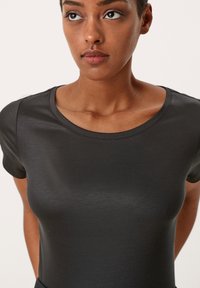 Zwarte aansluitende t-shirt gemaakt van een gladde stof, met een ronde halslijn en korte mouwen, die de gestroomlijnde silhoeet versterkt.