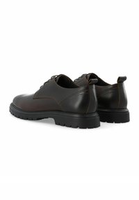 Zapatos de cuero marrón con un acabado texturizado, un perfil bajo, un diseño de cordones y una suela de goma negra resistente. Acentuados con costuras en contraste.