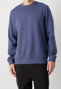 Blå crewneck sweatshirt i mjukt material, med en liten logotyp på bröstet och ribbade mudd och nederkant för en bekväm passform.