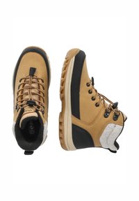 Des chaussures de randonnée marron et noires présentent une tige en cuir texturé, une doublure en fausse fourrure et une semelle en caoutchouc durable avec un relief multidirectionnel.