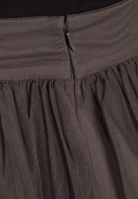 Grauer Tüllrock mit gerafftem Design, Reißverschluss an der Taille und einer weichen, strukturierten Oberfläche.