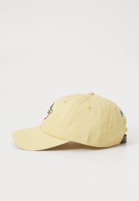 Yellow cotton baseball cap with a curved brim, featuring embroidered designs on the front and side. Adjustable strap at the back.