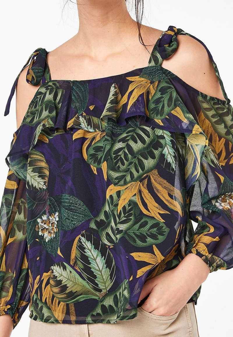 Blusa floreale off-the-shoulder in blu scuro con motivi di foglie verdi e gialle, scollatura arricciata e nastri sui bretelli. Tessuto leggero.