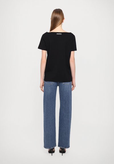 T-shirt noir à manches courtes avec un large décolleté, en coton doux, avec un logo au dos, associé à un jean large taille haute.