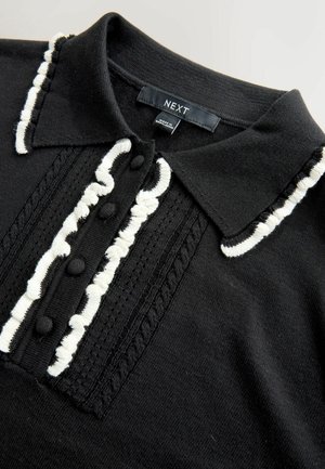 Schwarzes Strick-Polohemd mit weißen strukturierten Akzenten, einer Knopfleiste und einem Kragen mit kontrastierenden Abnähern und dekorativer Stickerei.