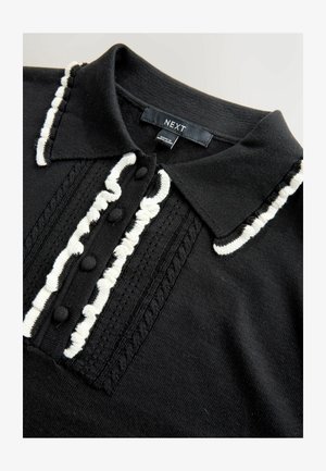 Must mustrikpolo, mis sisaldab valgeid tekstuuriaktsente, nööpide rida ning krae, millel on kontrastne ääre veel dekoratiivne õmblus.