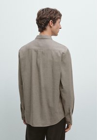 Light brown long-sleeve shirt with a smooth texture, featuring a classic collar and back pleat detail, shown from the rear.