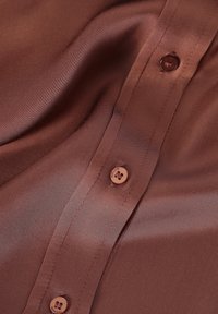 Brown satin shirt with a smooth texture, featuring a button placket, five round buttons, and subtly stitched detailing.