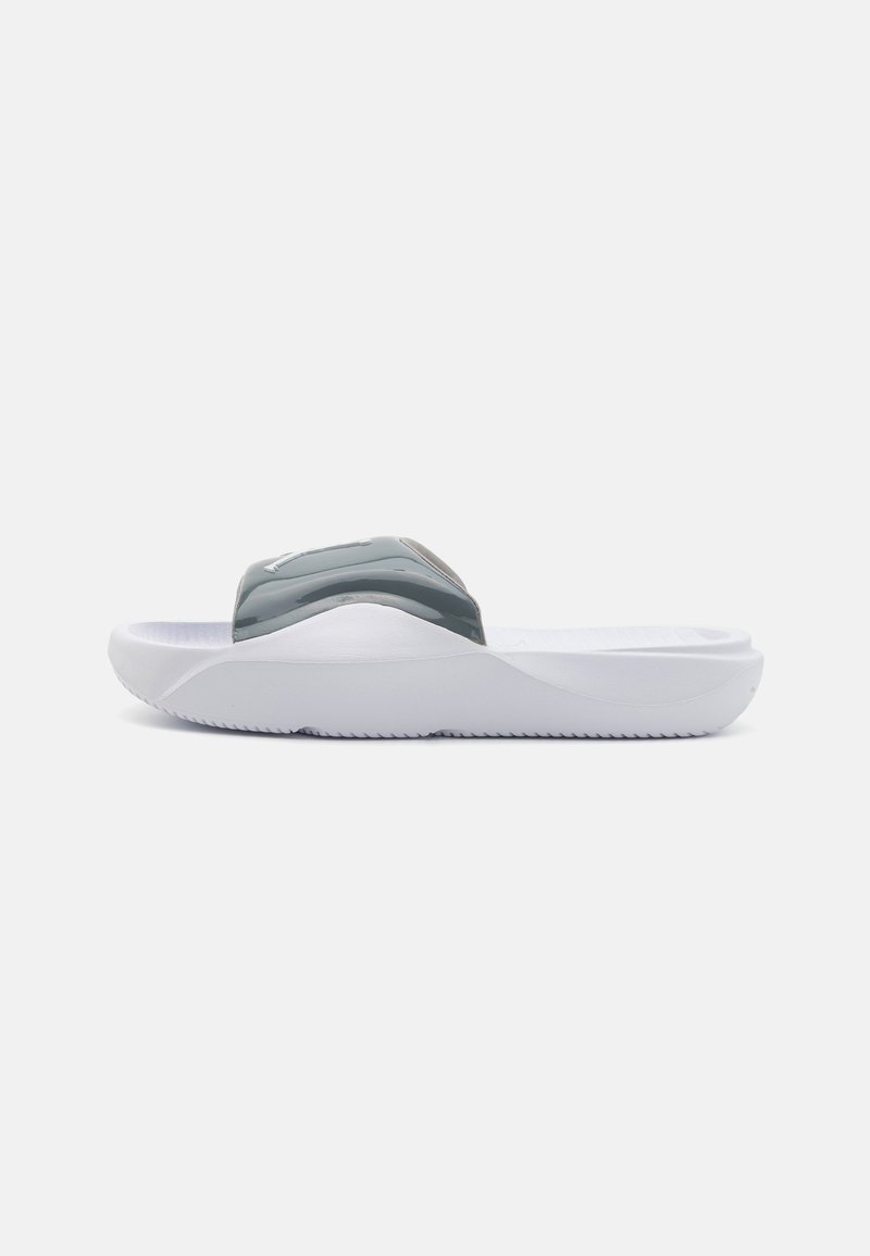 Grå slidesandal med en glansfuld rem og hvid sål. Sålen har et struktureret mønster for greb. Glat overflade, minimalistisk design.