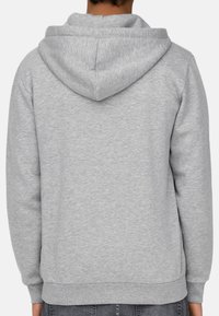 Light gray hoodie made of soft, textured fabric. Features a spacious hood, long sleeves, and a ribbed hem. Designed with a relaxed fit.