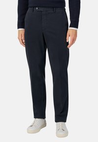 Chinos navy de tela suave con corte recto, con cierre de botón y bolsillos delanteros, combinados con zapatillas blancas.