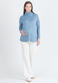 Sininen poolopaita rentoa istuvuutta, pitkät hihat ja sivuhalkiot. Yhdistetty valkoisiin leveälahkeisiin housuihin ja vaaleisiin lenkkareihin.