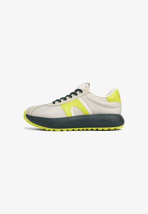 Zapatillas de cordones en malla beige y amarilla con suela gris oscuro. Presenta cordones verdes y detalles de acento en el costado y el talón.