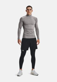 Hallide hallaste varrukatega sportlik särk, mustad lühikesed püksid ja mustad leggingud; valged spordijalatsid; sobiv kujundus, millel on logo aktsendid riietel.