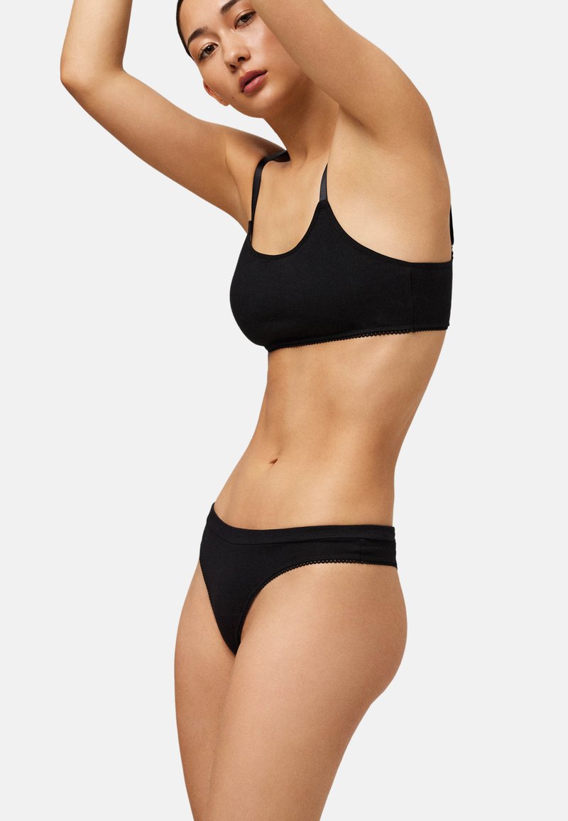 Conjunto de sujetador y bragas negras, con tela suave, diseño ajustado y delicado borde festoneado en los bordes.