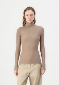 Langermet genser med høy hals i ribbestrikket stoff i tan; tettsittende design med ermer til håndleddet og en sømløs kant.