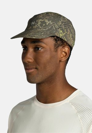 Man wearing a green patterned cap with ventilation holes and a light-colored, perforated sports shirt, facing slightly right.